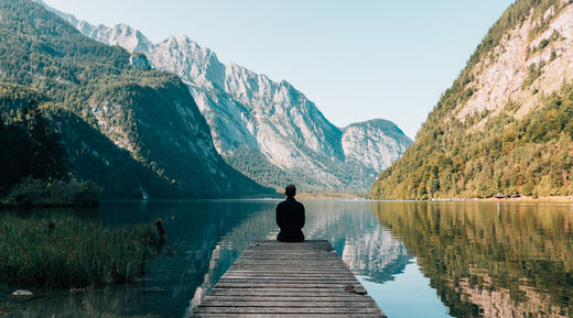 A person sitting on a dock on a lake between two mountains. The picture is paired with a blog post on "Preventative Health Care: What Is It and Why Is It Important?".