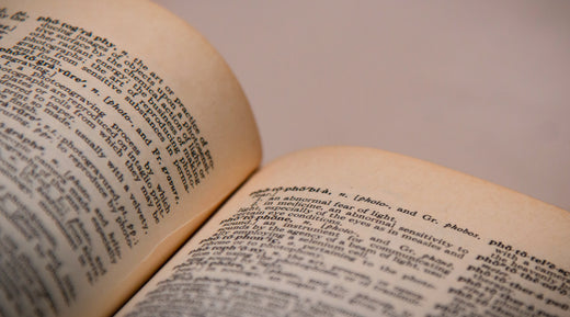 A close up of a romantically lit dictionary; the words in it not exactly legible. It is paired with a Forage Hyperfoods blog "The Medicinal Mushroom Glossary".