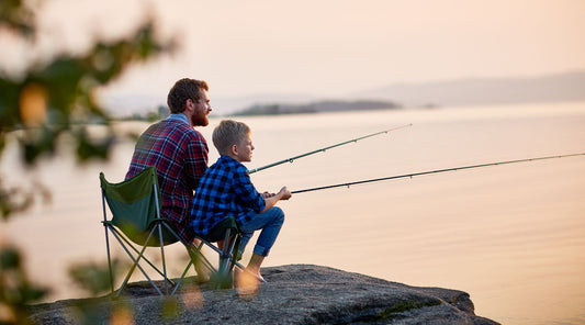 A father and son fishing together at golden hour.