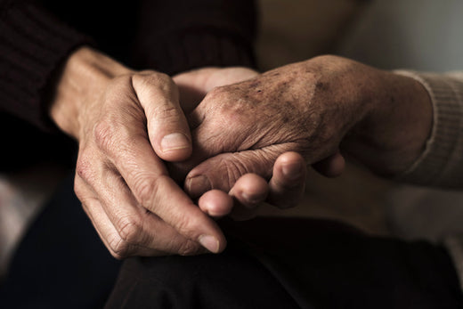 An elderly pair of hands on a black background alongside the Forage Hyperfoods blog post of "Using Chaga for Cancer: Here's What we Know".