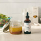 A Forage Hyperfoods Chaga tincture in the original format next to a healthy salad dressing, which the tuncture has been added to showing its everyday ease of use. Easy to apply to your day to day foods.