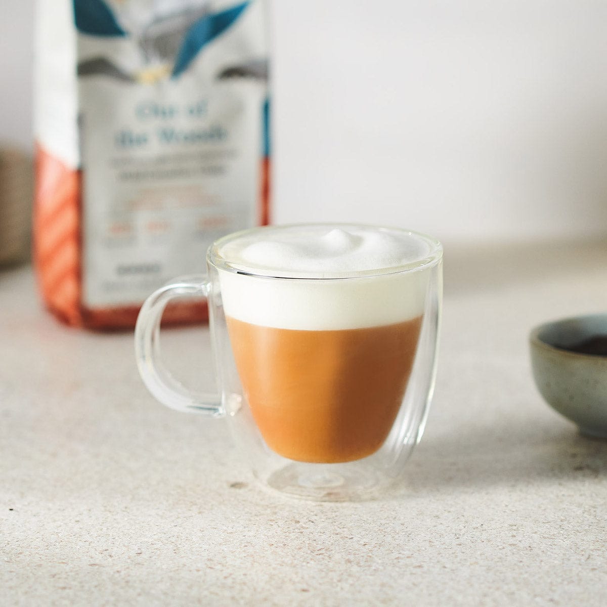 A foamed transparent cup of Chaga-infused coffee. It is a creamy, smooth and delicious coffee in a light brown color.