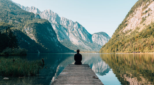 A person sitting on a dock on a lake between two mountains. The picture is paired with a blog post on "Preventative Health Care: What Is It and Why Is It Important?". 