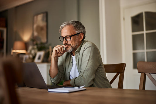 A confident senior male freelancer reading a document on a laptop.
