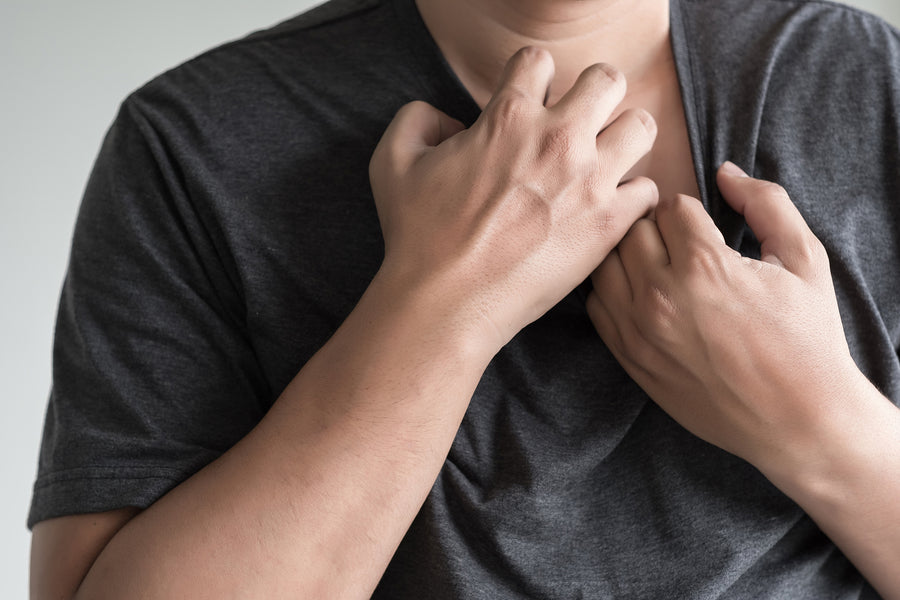 A man in a gray shirt scratching at his skin. The picture is paired with a blog titled "Chaga for Psoriasis: Can It Help?". 