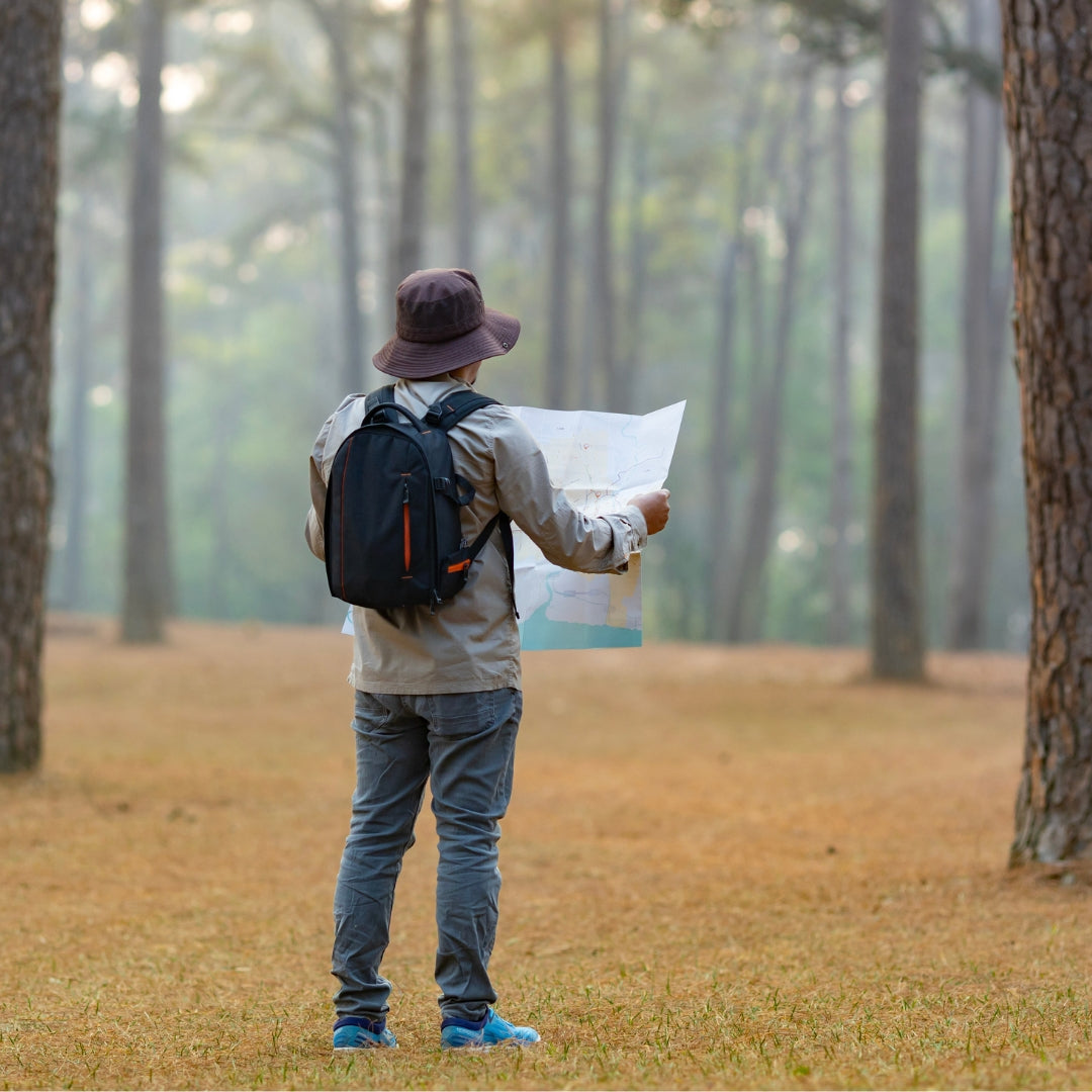 A man in the woods looking at a map, indicating guidance for wellness. 