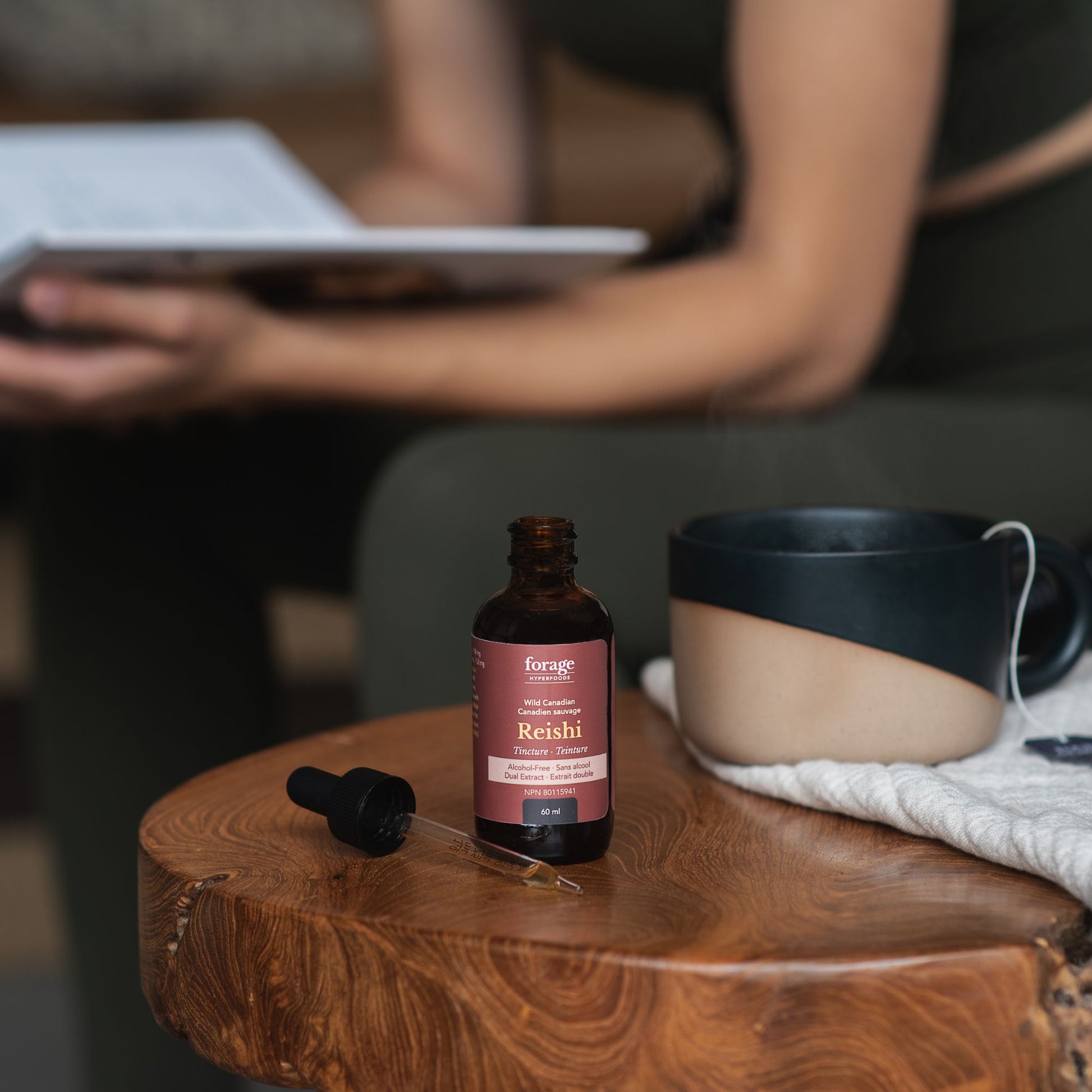 Reishi Alcohol Free format in a tincture, at home with a person reading in the background. 