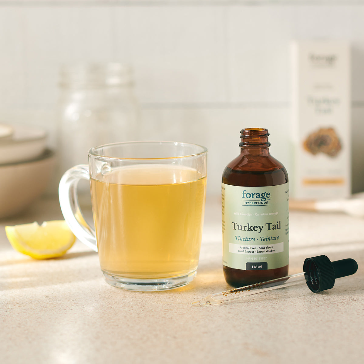 A alcohol-free turkey tail tincture next to a healthy lemon tea in a glass jar demonstrating the ease of use. 