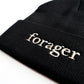A close up of a black beanie with the word "forager" on it. 