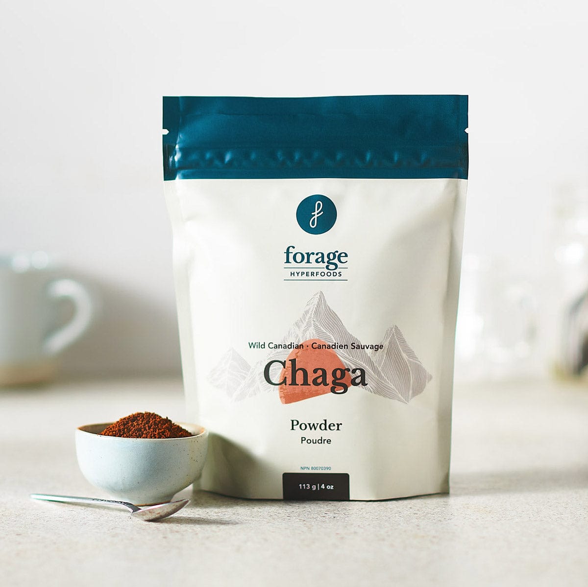 A bag of Canadian Chaga Powder by Forage Hyperfoods with a bowl of Powdered Chaga mushroom next to it.