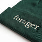 A close up of a green beanie with the word "forager" on it. 