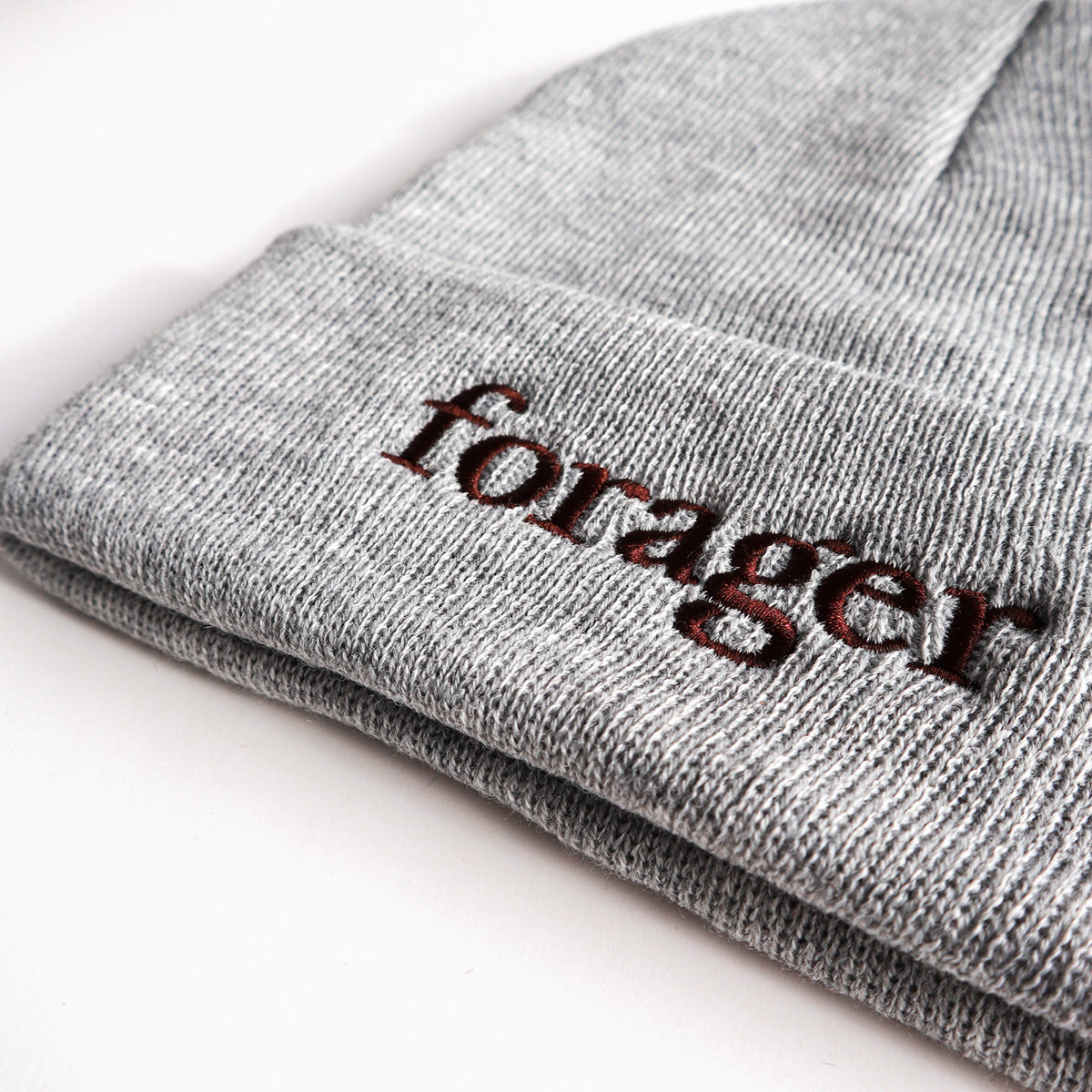 A close up of a gray beanie with the word "forager" on it. 