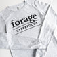 A light gray shirt with the word mark "Forage Hyperfoods" printed on it in black. It is laid out flat on a white background. 